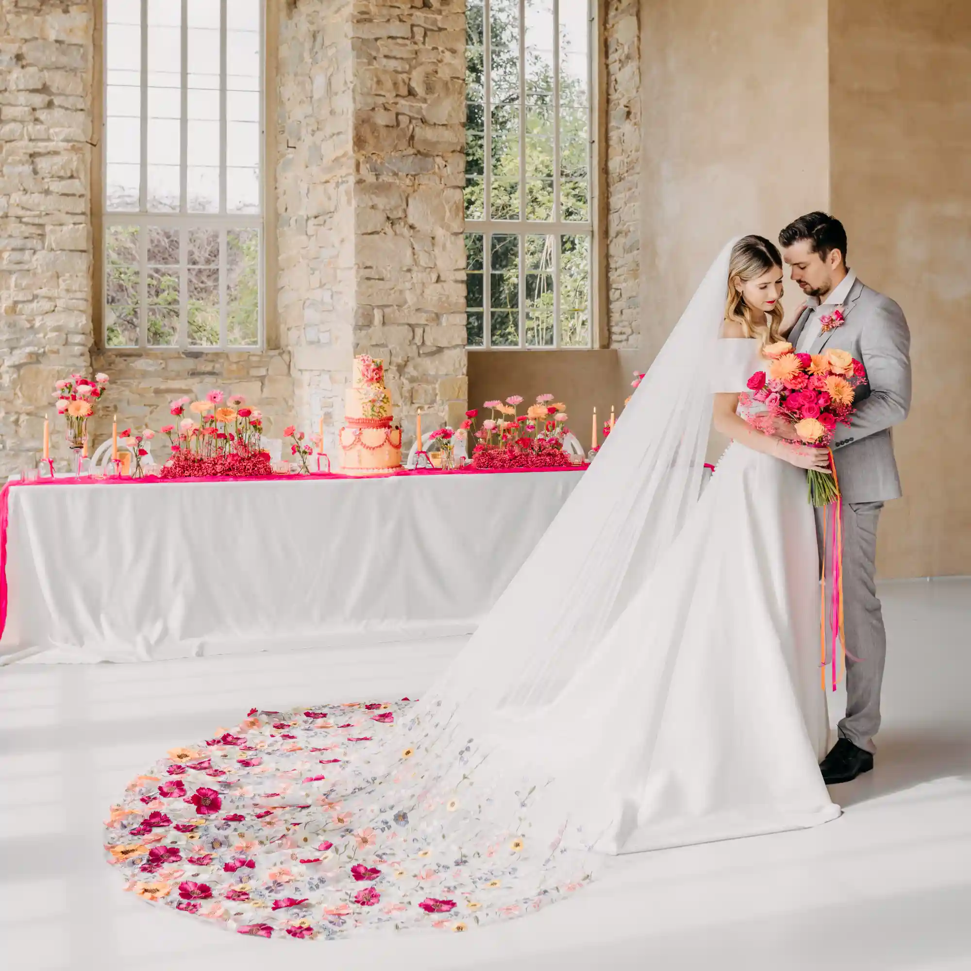 Farbintensive Hochzeitstorte mit frischen Blumen und goldenen Akzenten, dekoriert auf einer festlichen Tafel.